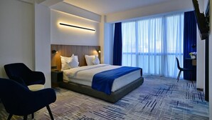 Una habitación de hotel moderna con una cama grande, un escritorio y una televisión.