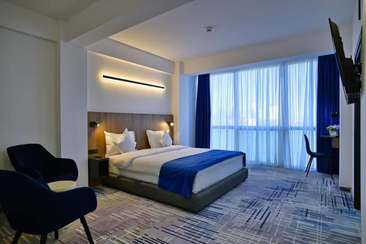 Una habitación de hotel moderna con una cama grande, un escritorio y una televisión.