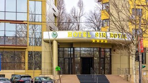 Un edificio con un letrero que dice "HOTEL SIR ROYAL" y un logotipo con tres estrellas.