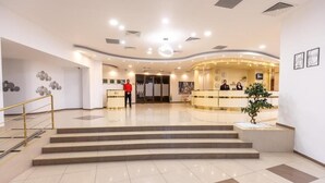 Un vestíbulo de hotel con una recepción, una escalera y un área de recepción.