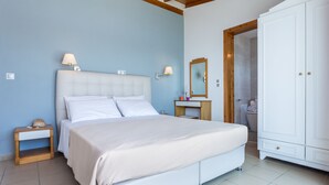 A bedroom with a large bed, bedside tables, a vanity with a mirror, and a wardrobe. - Hotel Akti (Skiathos)
