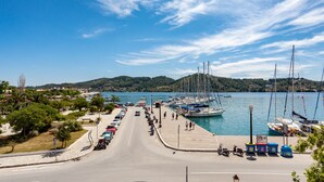 A marina with boats docked, a road leading to the marina, and a clear blue sky. - Hotel Akti (Skiathos)