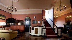 Un'ampia hall con un'imponente scalinata, una reception e una zona salotto confortevole.