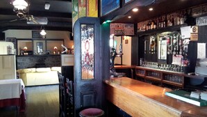 Un'area bar con sgabelli, un bancone e diverse bottiglie.