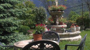 Un jardin avec une fontaine, des chaises et une vue sur la montagne.