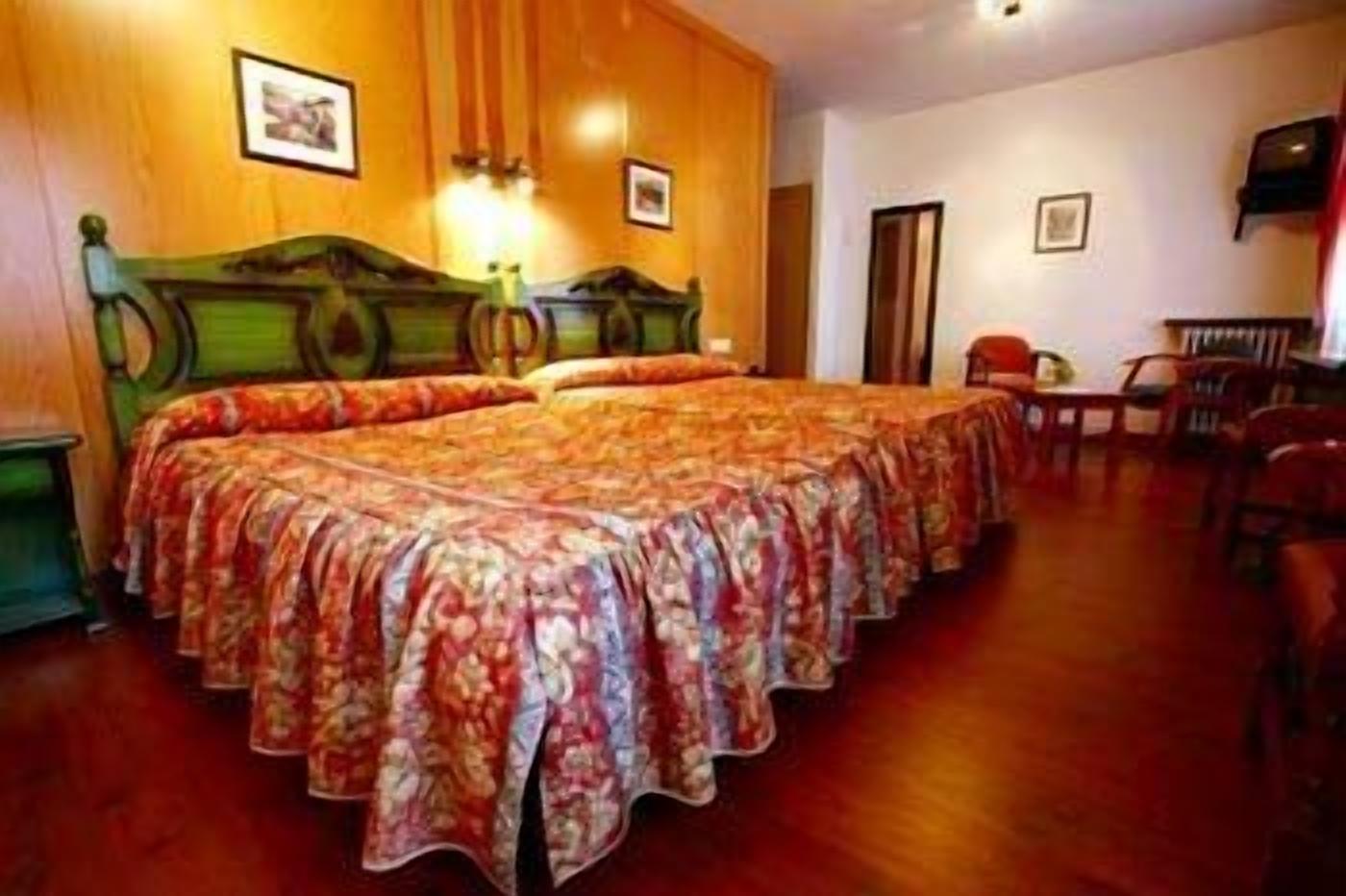 Una habitación de hotel con una cama grande, un cabecero de madera, una mesita y una silla.