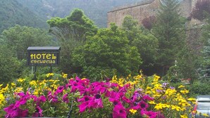 Une enseigne indiquant un hôtel appelé «Hotel Edelweiss», entourée de fleurs aux couleurs vives et d’une végétation luxuriante.