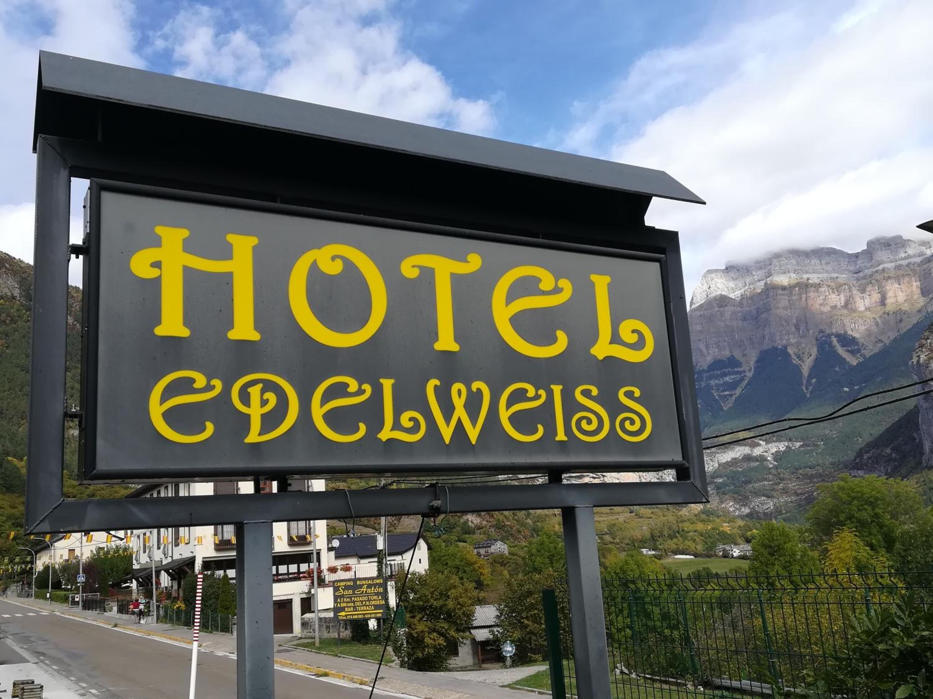 Une enseigne pour l’hôtel Edelweiss, avec un paysage montagneux en arrière-plan.