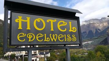 Une enseigne pour l’hôtel Edelweiss, avec un paysage montagneux en arrière-plan.