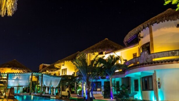 A nighttime resort with a swimming pool, thatched-roof structures, and ambient lighting. - Hotel Il Nuraghe (Aracati)