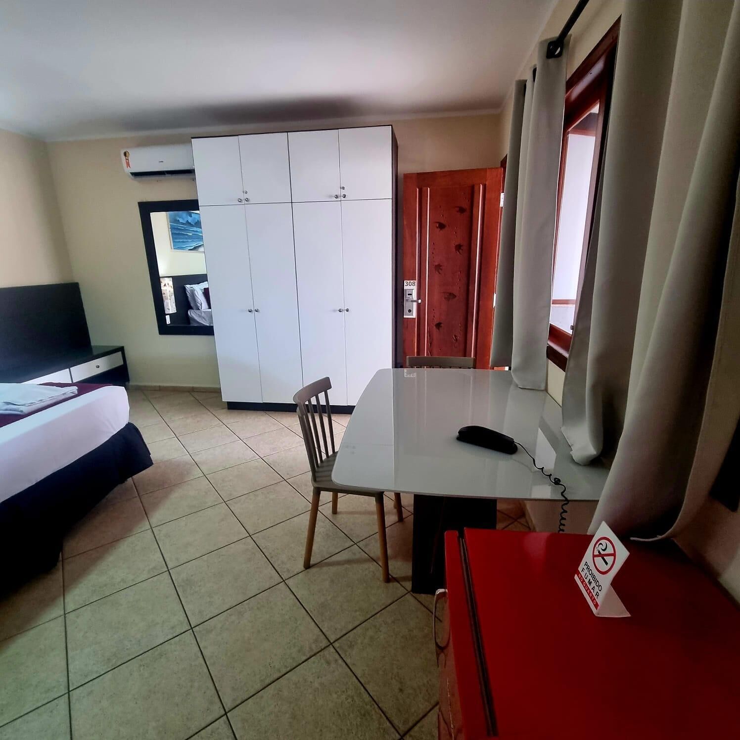 Una camera d'albergo con un letto, una scrivania, una sedia, un armadio e una televisione.