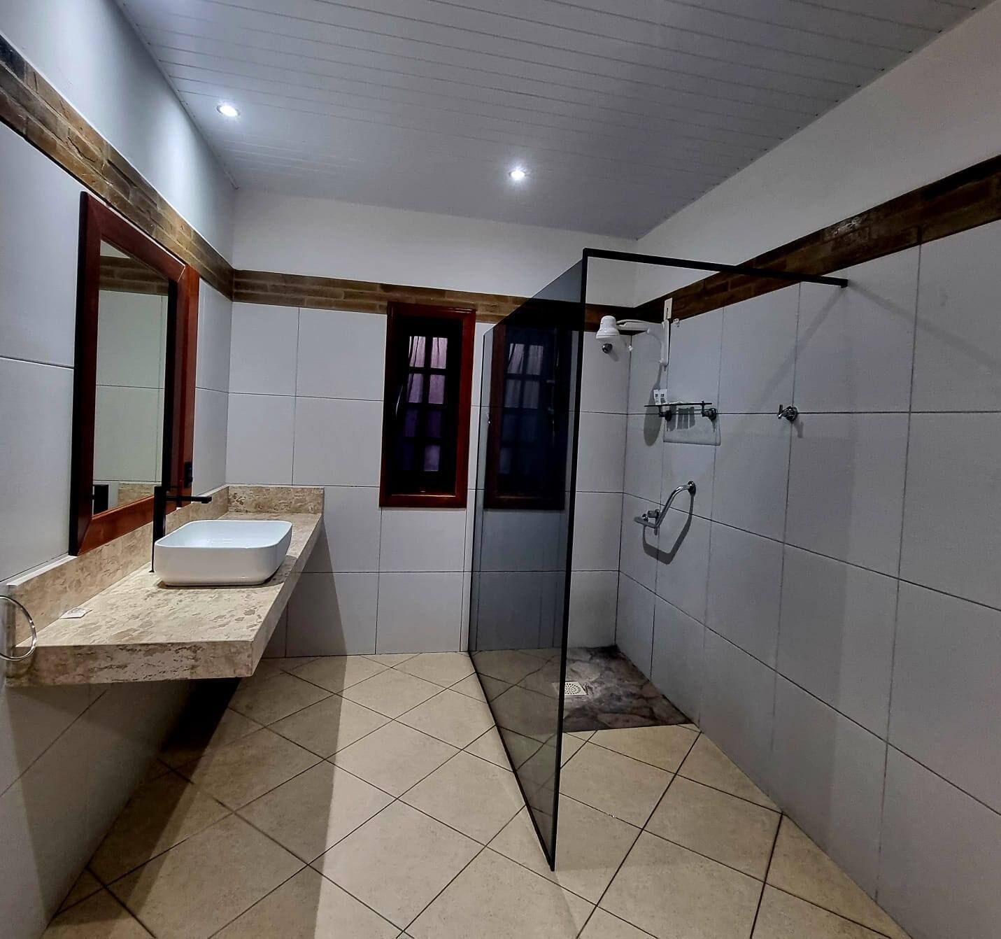 A bathroom with a large mirror, a sink, and a shower area.