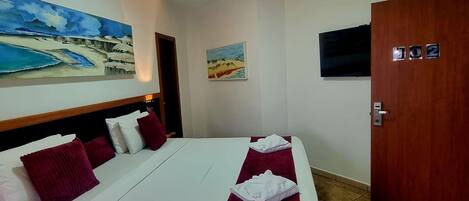 Een hotelkamer met een bed, een televisie en twee schilderijen aan de muur.