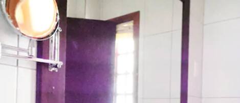 A bathroom with a white sink, a large mirror, and a purple-tiled wall.