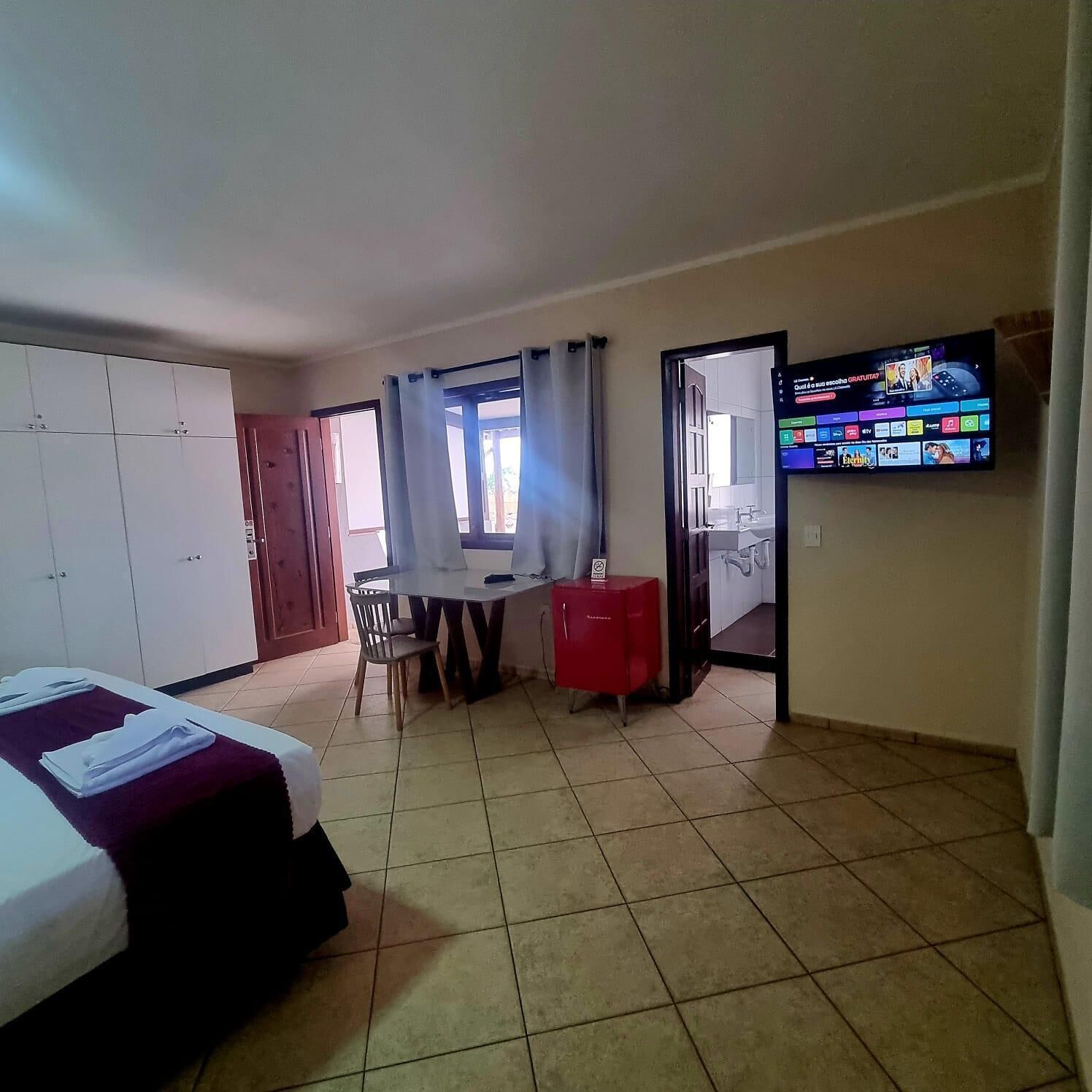 A hotel room with a bed, a desk, a chair, a TV, and a wardrobe.
