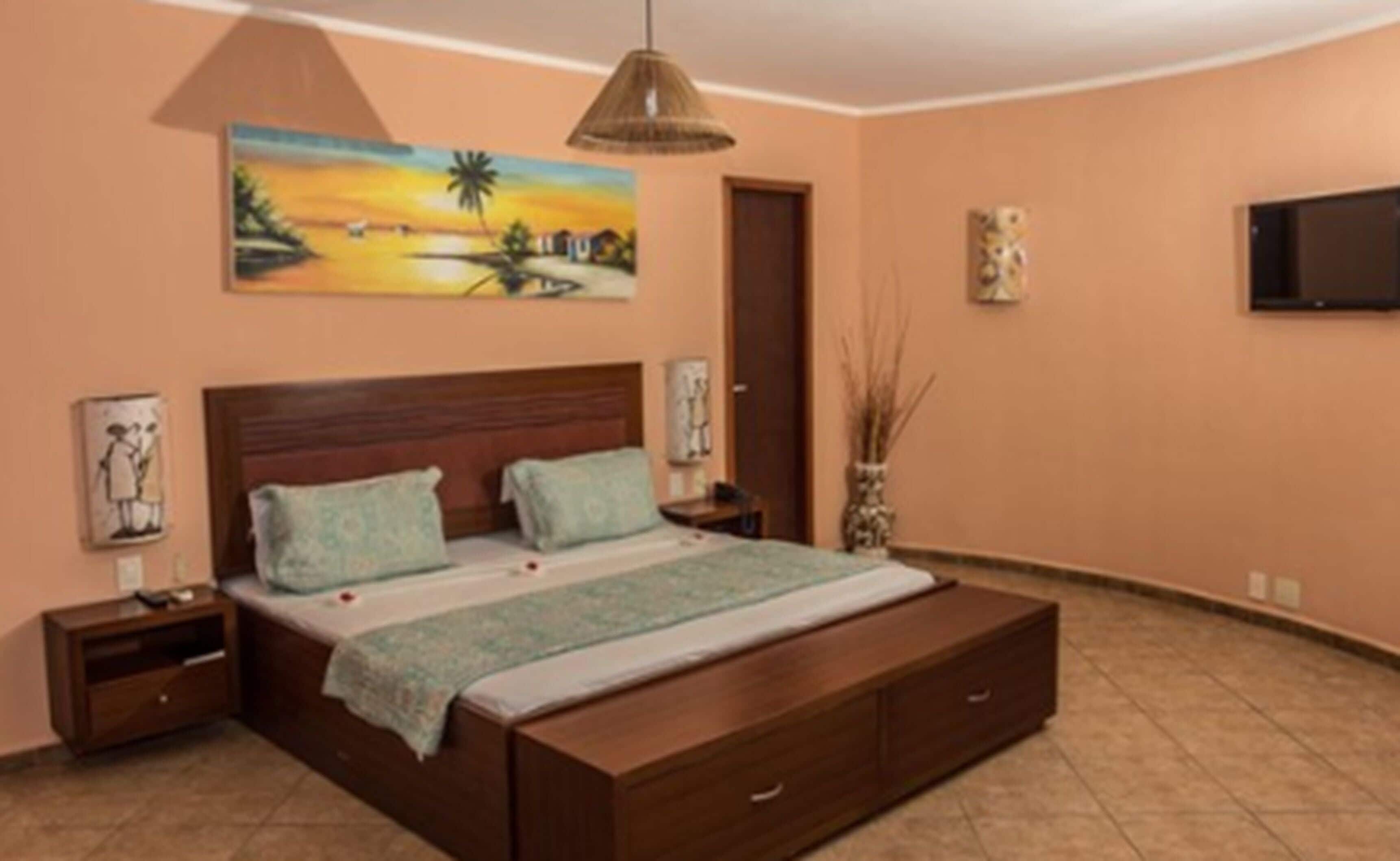 A bedroom with a large bed, nightstands, a TV, and a painting on the wall.