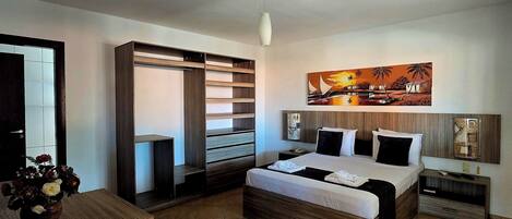 Quarto moderno com cama grande, armário embutido e um quadro na parede.