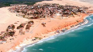 An aerial view of a coastal town with a beach, houses, and a road leading to the sea. - Hotel Il Nuraghe (Aracati)