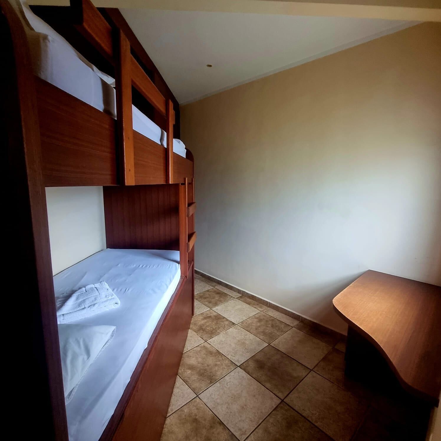 Una habitación con literas, una mesita pequeña y suelo de baldosas.