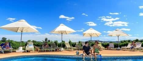 Een buitenzwembad, parasols voor strand/zwembad