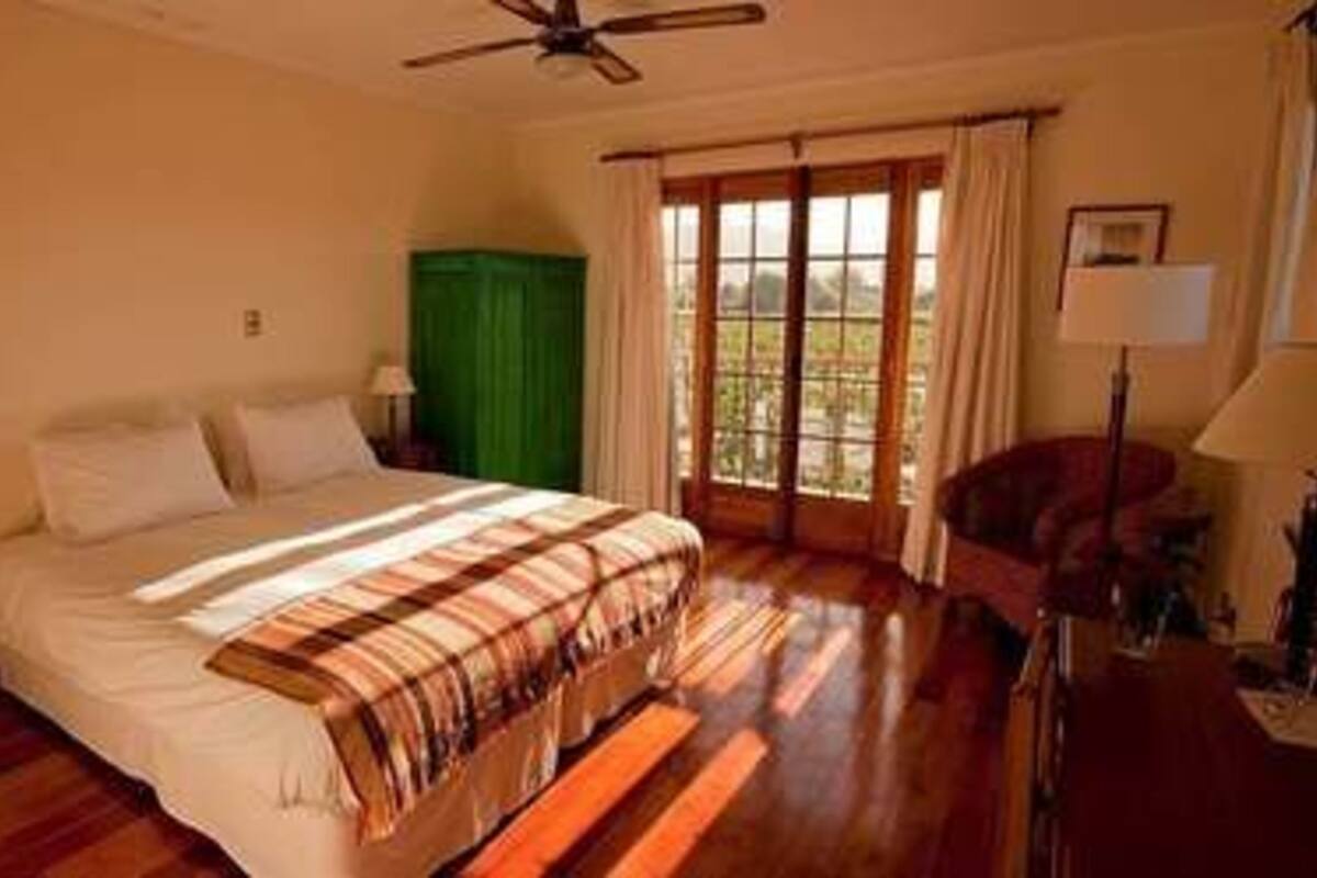 A bedroom with a bed, a green cabinet, a window with curtains, and a ceiling fan.