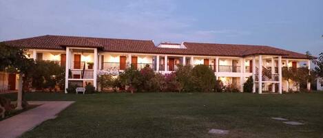 A two-story building with a tiled roof, multiple balconies, and a well-maintained lawn.