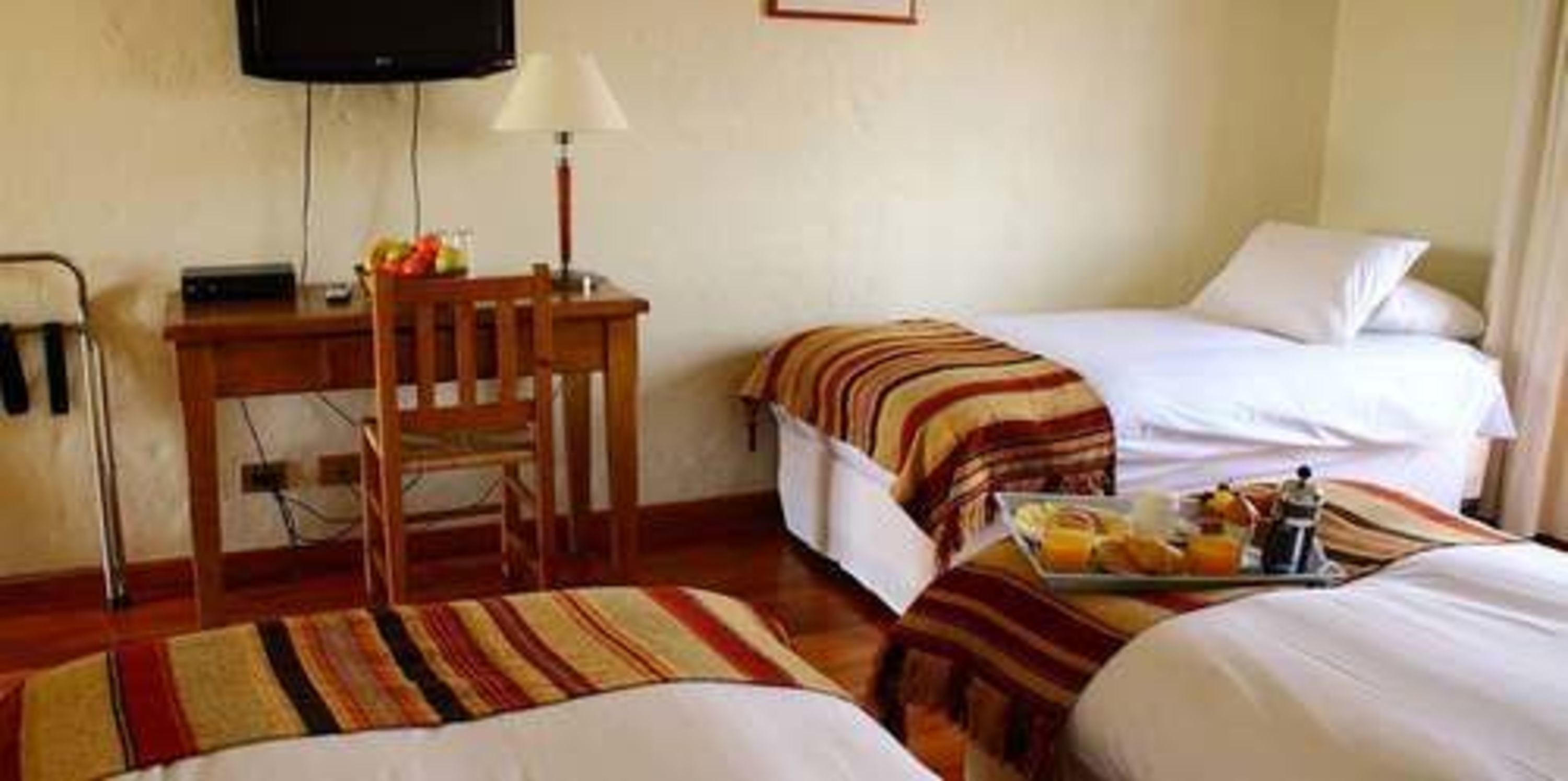 Una habitación de hotel con dos camas, un escritorio, una silla y un televisor.