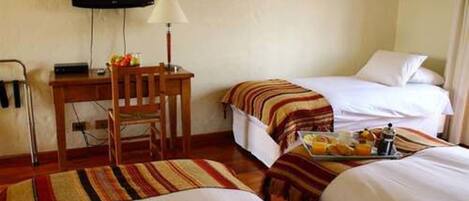 Una habitación de hotel con dos camas, un escritorio, una silla y un televisor.