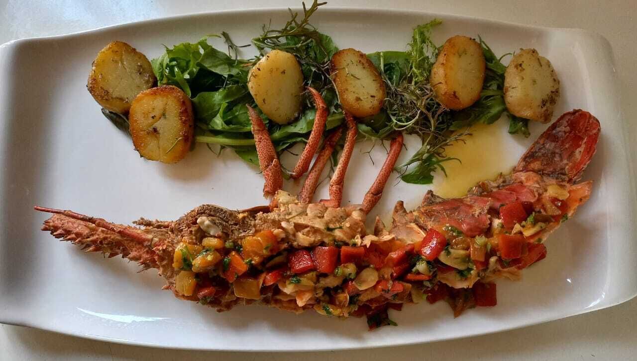 A plate with a cooked fish, potatoes, and greens.