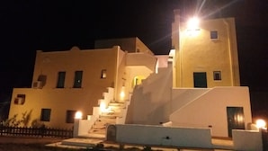 A multi-story building with a staircase leading to the upper levels, illuminated by exterior lights.