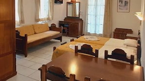A cozy room with a wooden bed, a wooden sofa, a dining table with chairs, and a desk.