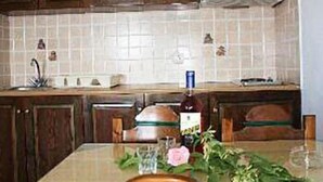 A kitchen with wooden cabinets, a tiled backsplash, and a table set with a bottle, glasses, and a flower.