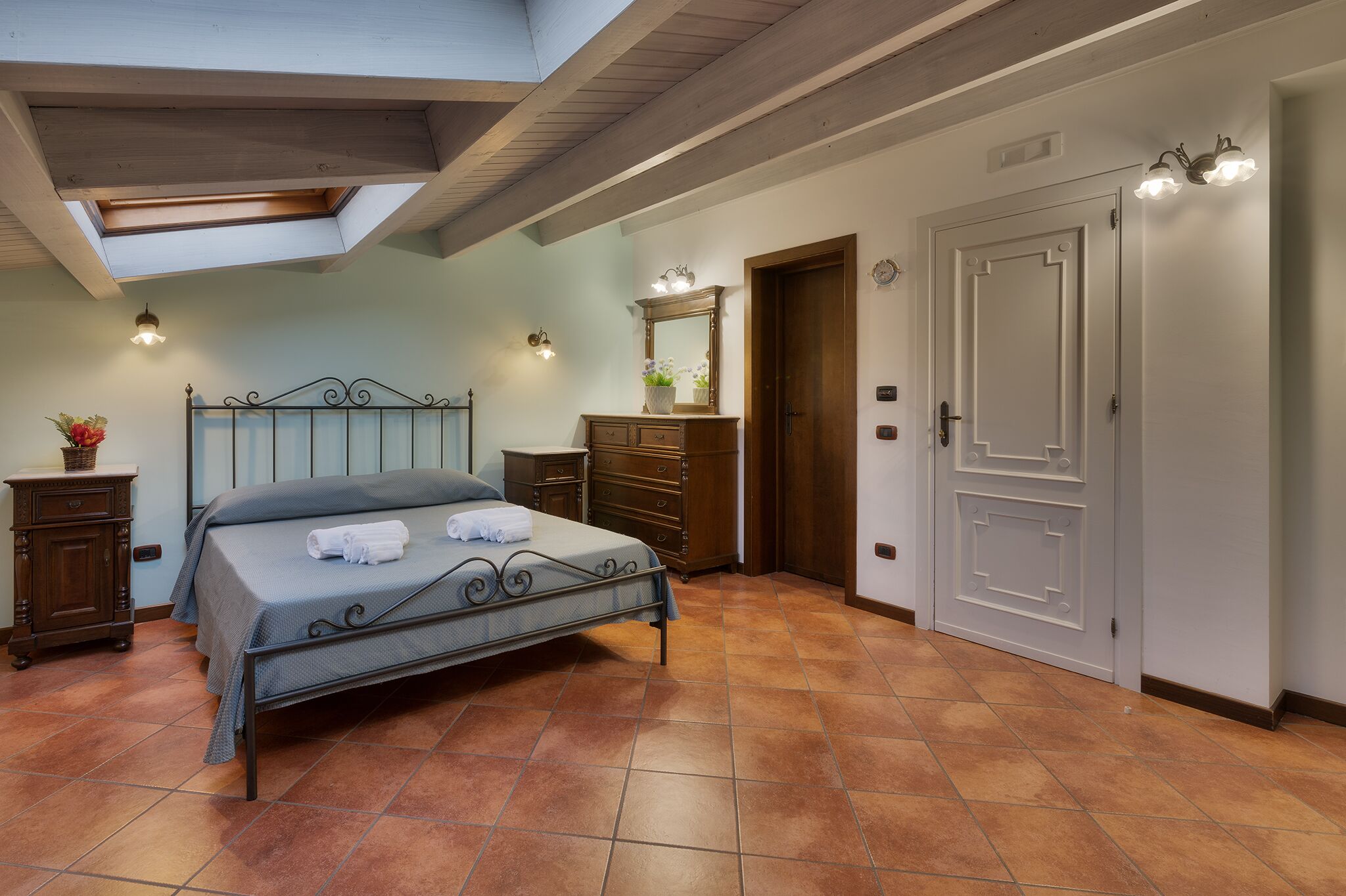 A bedroom with a bed, a dresser, a mirror, and a door.