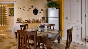Un comedor con piso a cuadros, sillas de madera, una mesa de vidrio y una puerta blanca.