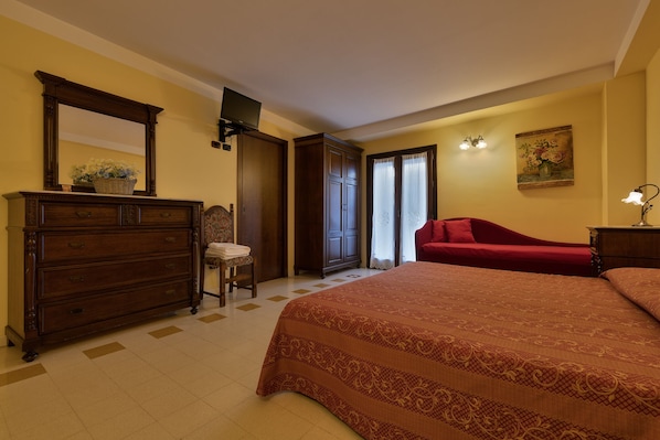A bedroom with a large bed, a dresser, a chair, a television, and a painting on the wall.