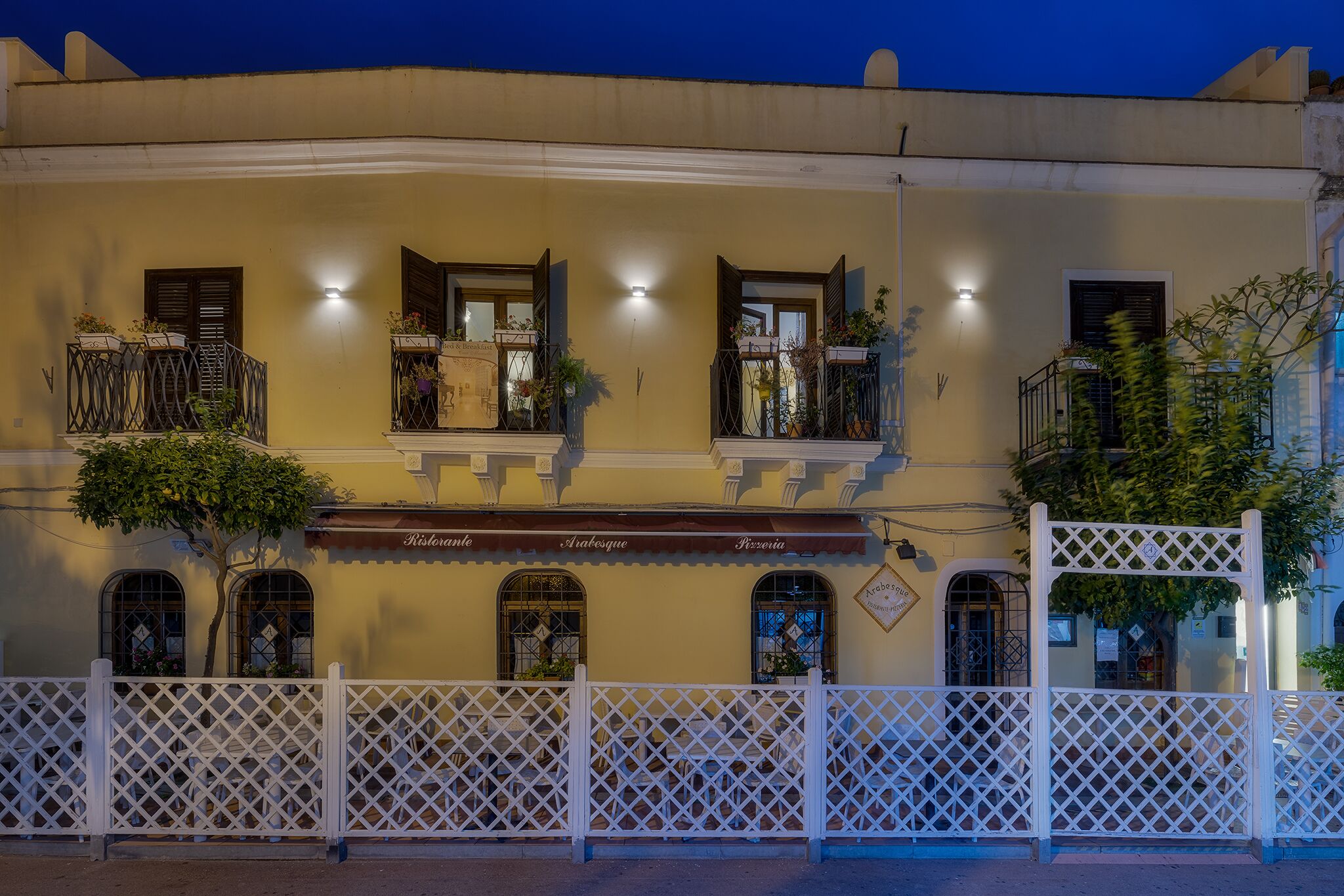 A building with multiple balconies, a white fence, and a sign with the word "Ristorante".