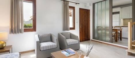 A modern living room with two grey armchairs, a wooden coffee table, and a book.