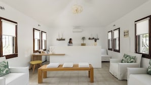 A spacious living room with a wooden coffee table, white sofas, and a central island with a small kitchen area. - Trikorfo Beach (Polygyros)