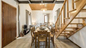 A dining area with a wooden table and chairs, a television, and a staircase. - Trikorfo Beach (Polygyros)