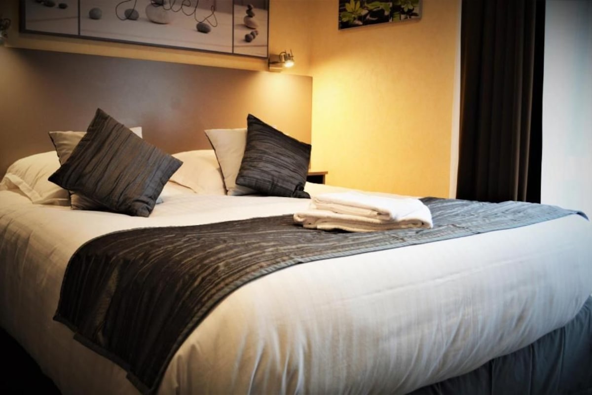 A neatly made bed with pillows, a folded towel, and a blanket.
