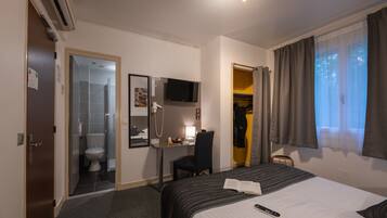 Une chambre d’hôtel équipée d’un lit, d’un bureau, d’une chaise, d’une télévision, d’une douche et d’une armoire.