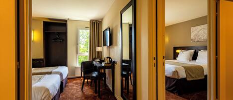 A hotel room with two single beds, a desk with a chair, a television, and a large mirror.