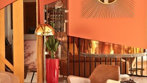 Un interior moderno con un sillón de cuero marrón, una planta en maceta roja y un espejo de sol original.