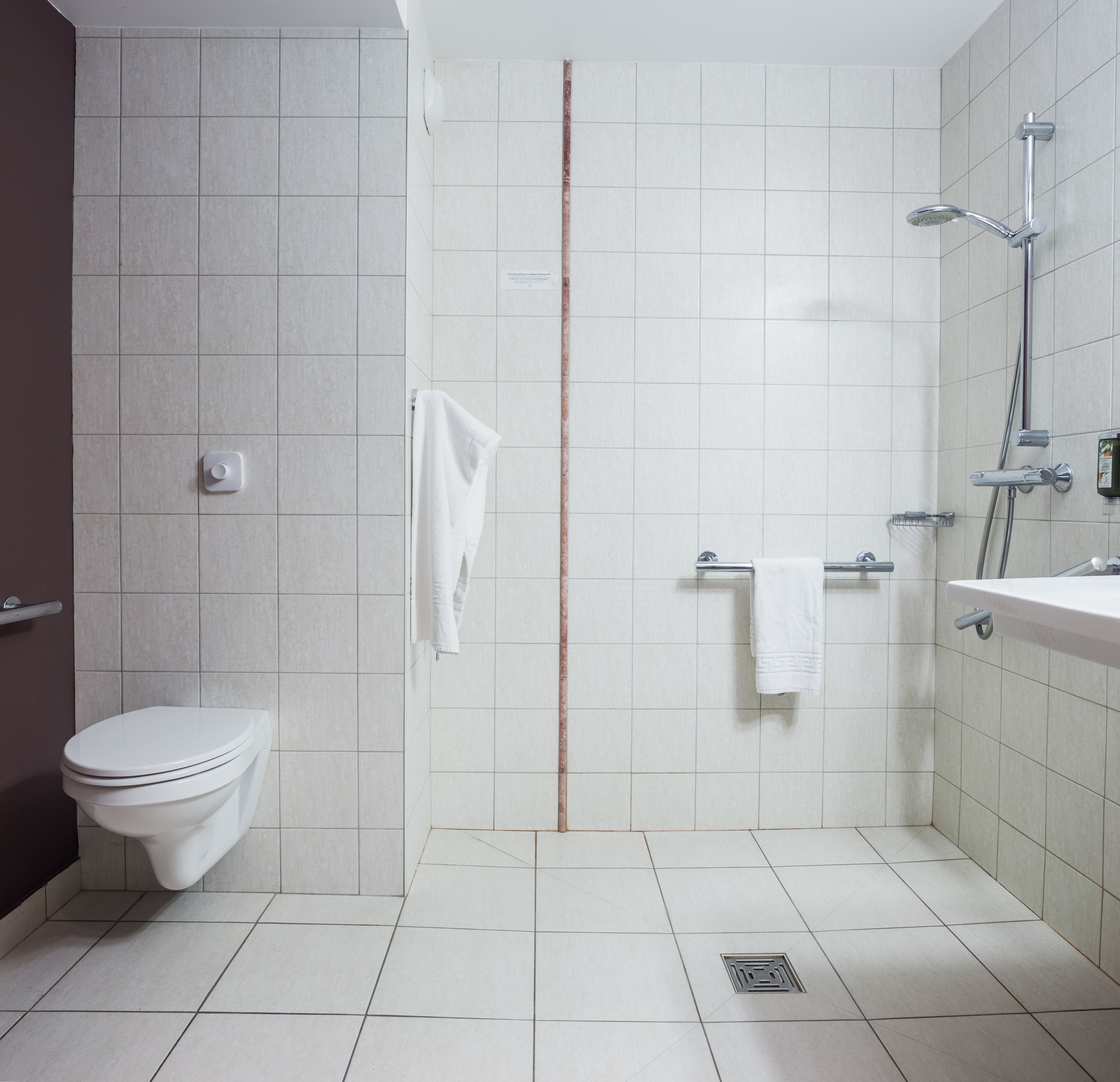 A modern bathroom with a toilet, a shower, and a sink.