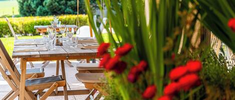 Un área de comedor al aire libre con una mesa de madera dispuesta para una comida, rodeada de sillas.
