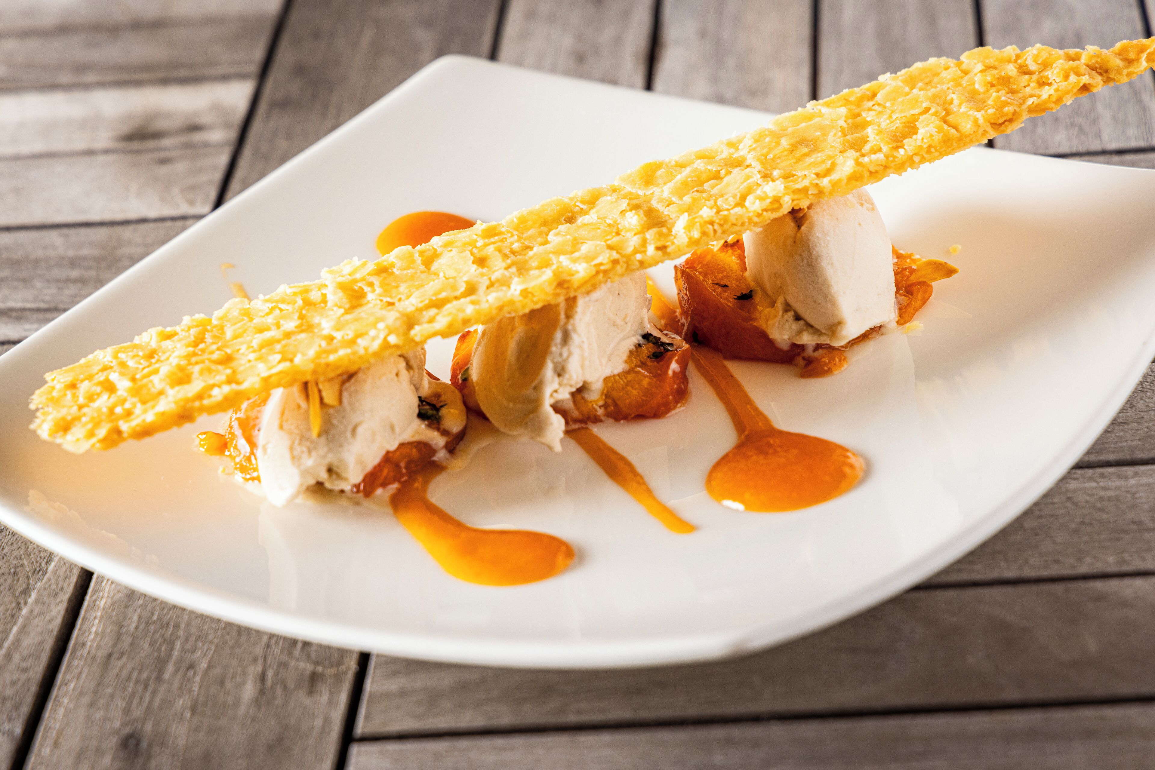A square white plate with a piece of food on a wooden table.