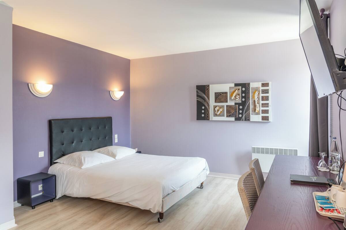 Un dormitorio con cama, mesitas de noche, un escritorio y una obra de arte colgada en la pared.