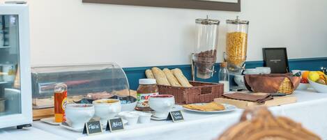 Un buffet de petit-déjeuner proposant divers plats, une machine à café et un tableau représentant un paysage urbain accroché au mur.
