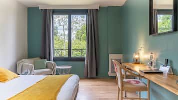 A room with a bed, a desk, and a chair. There is a window with curtains, a lamp, and a bottle on the desk.