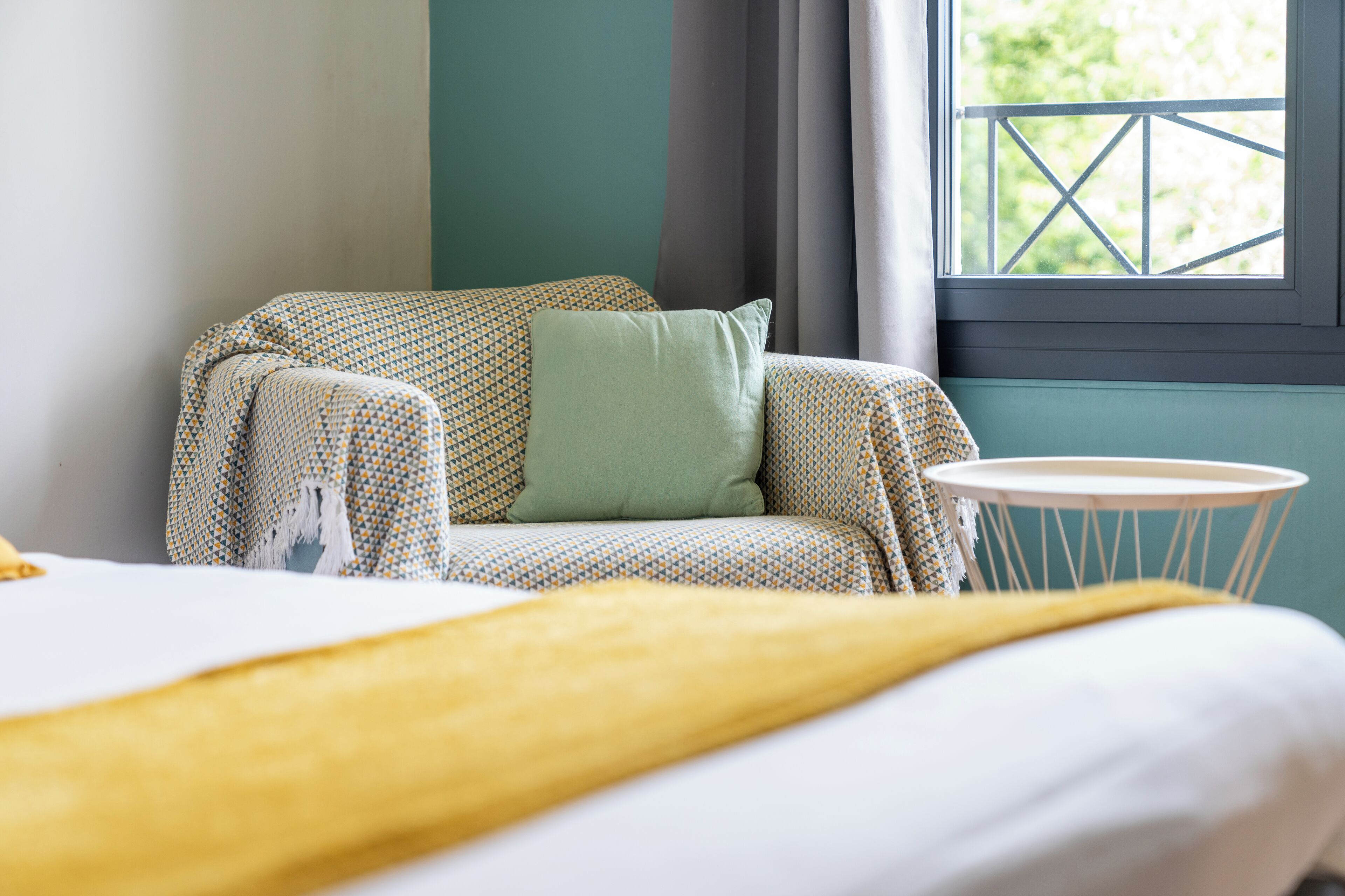 Una habitación acogedora con una cama, una mesita redonda y una ventana con vistas a zonas verdes.